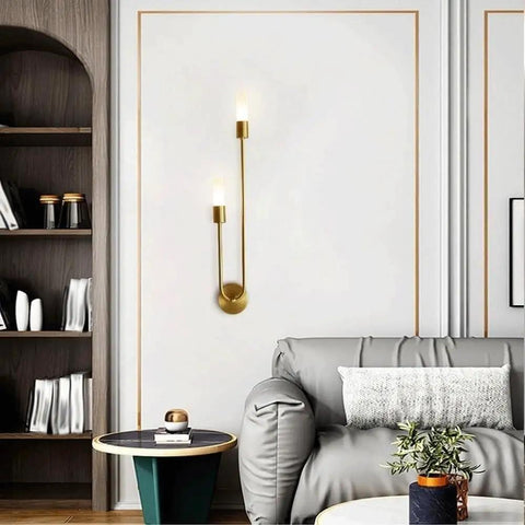 UPRENXIAO Modern Wall Sconce Linear Curved Design Up Down Lighting Ambient(Gold) on a white wall beside a gray sofa.