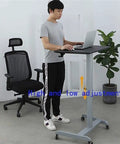 Height Adjustable Mobile Standing Desk With Smooth Roll Wheels Built Tough Rust Resistant Steel Laptop Lectern Workstation Spacious Matte Black Surface No Extra Fluff Office Or Home Setup in use by a man