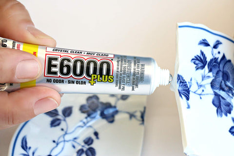 Hand applying Clear Multipurpose Adhesive For DIY Projects With Low Odor Self Leveling And Flexible Bond to broken ceramic vase.