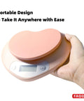 Hand holding portable digital kitchen scale with LCD display, pink finish, 11 lb capacity, ultra accurate 0.03 oz increments, easy tare