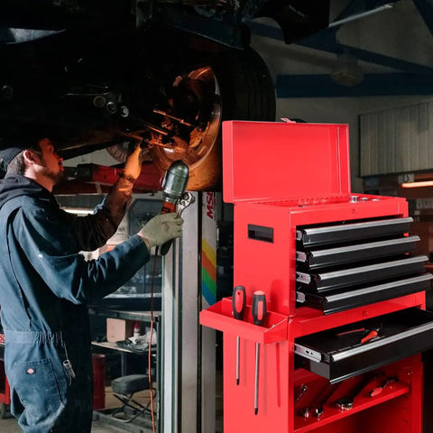 Five Drawer Rolling Tool Chest With Lockable Cabinet On Heavy Duty Wheels For Garage And Workshop Detachable Removable Tool Storage In Cold Rolled Steel Red And Black Finish is open beside a mechanic working under a car