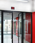 Ultra Bright Battery-Backed LED Exit Sign With Indoor Emergency Lighting And Chevron Arrow, installed above glass doors.