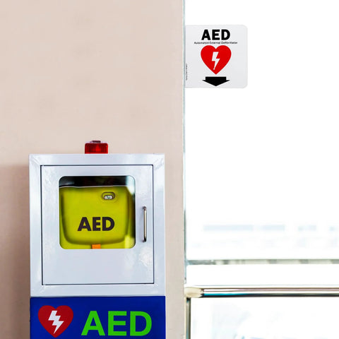 Front view of stainless steel AED cabinet with yellow AED inside; blue panel below and acrylic 6x6 sign with down arrow