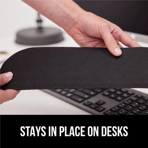 Person holding part of a Silky Memory Foam Wrist Rest For Keyboard And Mouse Ergonomic Design For Typing Pain Relief Two Piece Desk Pad Set Stain Resistant Black Crazy Comfy Fits Most Desks in front of a keyboard.