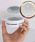 Hand installing No Drilling Magnetic Smoke Alarm Mounts 3 Pack With Adhesive Pads on ceiling, close-up view