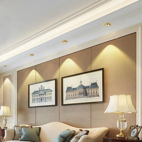 Polished 4.5 Inch Adjustable Recessed Ceiling Light In Warm Brass Finish illuminating framed artwork in a modern living room.