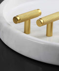 Brushed gold knurled cabinet pull handles on a white marble tray, showcasing design similar to the 10 Pack Knurled Black Cabinet Pulls For Cabinets And Drawers With 9.8 Inch Length And 7.5 Inch Hole Spacing, Easy One Screwdriver Install, Slick Knurled Texture, Durable Cupboard And Dresser Handles, Modern Home Hardware Update.