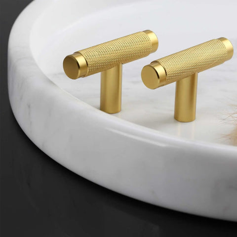 Brushed gold knurled cabinet pull handles on a white marble tray, showcasing design similar to the 10 Pack Knurled Black Cabinet Pulls For Cabinets And Drawers With 9.8 Inch Length And 7.5 Inch Hole Spacing, Easy One Screwdriver Install, Slick Knurled Texture, Durable Cupboard And Dresser Handles, Modern Home Hardware Update.