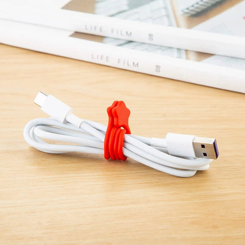Red Reusable Silicone Magnetic Cable Tie securing white USB cable on wooden desk