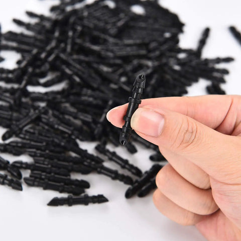 Close-up of hand holding 1/4 inch connector from 300 Pieces One Quarter Inch Single Barbed Drip Irrigation Fittings And Couplers Set