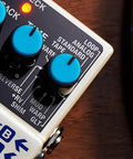 Close-up of Digital Delay Guitar Effects Pedal With 11 Modes, showing control knobs and input ports on a wooden surface.