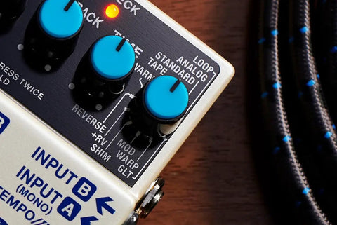 Close-up of Digital Delay Guitar Effects Pedal With 11 Modes, showing control knobs and input ports on a wooden surface.