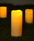 Large 4x10 Waterproof Outdoor Flameless Candles Battery Operated LED Pillar Lights with flickering effect on grass.