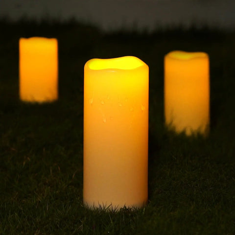 Large 4x10 Waterproof Outdoor Flameless Candles Battery Operated LED Pillar Lights with flickering effect on grass.