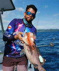 Man holding a large fish on a boat with ocean in background