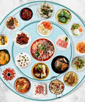 Super Smooth Tempered Glass Lazy Susan For Dining Table 360 Degrees Turntable displaying diverse dishes around a large round tray.