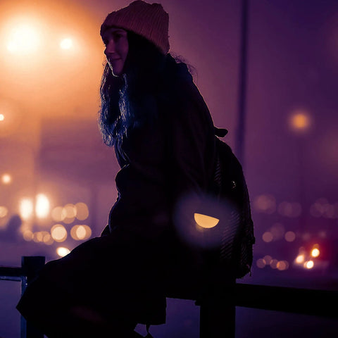 Silhouette of a person sitting with city lights in the background at night.