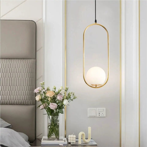 Modern One Light Globe Pendant With White Milk Glass Shade In Brushed Brass Finish For Kitchen Island Farmhouse Living Spaces Mid Century Style Ceiling Lighting Fixture hanging in a bedroom