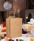Brown kraft gift bag with handles on festive table 26 Pack Brown Kraft Gift Bags With Handles Bulk Small Size Gift Bags 8.3 x 3 x 6 Inches Eco Friendly Durable For Cookies Pastries And Small Gifts Party Favors And Bulk Buying