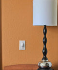 Room with a lamp and Childproof Light Switch Plate Covers 2 Pack White Safe Home Shield To Stop Little Ones And Curious Adults From Accidentally Flipping The Switch Easy Install Toggle Switch Shields next to the switch.
