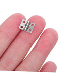 Lil Copper Miniature Hinges With Screws Pack Of 100 For Dollhouses And Tiny Boxes 10x8mm shown on fingertips for scale.