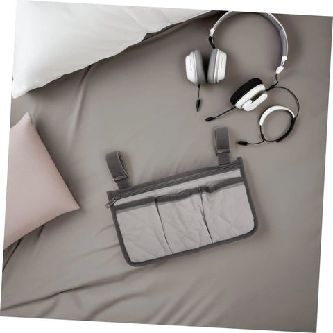 Gray bed rail organizer with dark trim and 4 pockets, shown next to headphones on a bed, for home, hospital, and care beds.