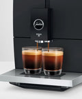 Smooth Operator Fully Automatic Coffee Machine Featuring A Smart Touchscreen And One Touch Milk Drinks In Polished Metropolitan Black brewing espresso into two glasses.