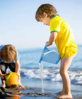 Children playing on beach with Six Piece Beach Buckets and Shovels Set for Kids, 7.6 Inch Pails by water.