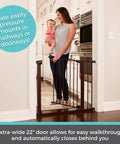 Stone Arch Auto Close Baby Gate For Doorways Bronze Metal Safety Gate, mom and baby standing behind tall gate at door.
