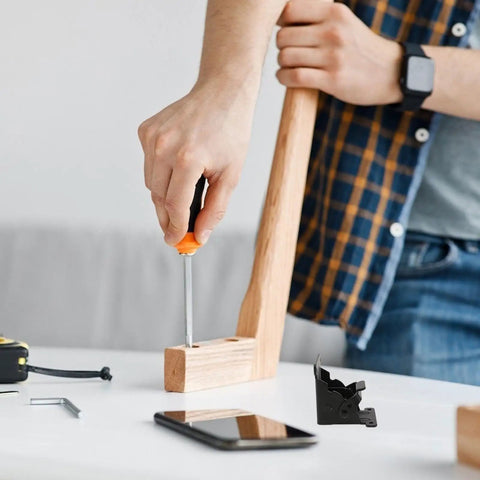 Person using screwdriver to install Heavy Duty Black Iron Folding Table Leg Hinges With Spring Two Pack For Tea Tables Easy Install