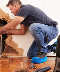 Man wearing blue non slip waterproof disposable shoe covers protecting floors while fixing wall pipe