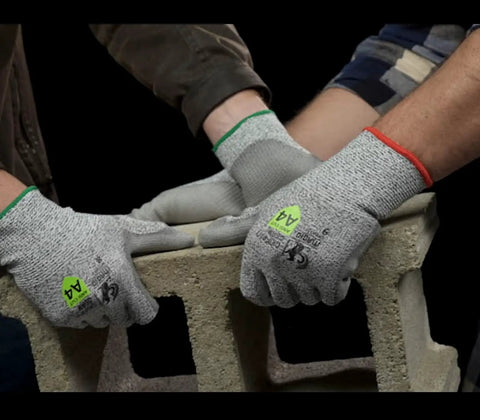 Top Shelf ANSI A4 Cut Resistant Work Gloves With Smooth Polyurethane Grip And Durable DuraBlend Shell Built Tough For Grease Monkey Tasks Providing Rock Solid Level 5 Abrasion And Level 4 Puncture Protection In Large Fits Bulk Pack Of 24 Pairs, worn while handling a concrete block.
