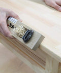 Beginner Friendly Japanese Woodworking Hand Tool Set 7 Piece Includes Plane Chisels Pull Saw Hammer Marking Gauge And Carry Bag All In One Starter Kit Made In Japan For DIY Woodworking Fans showing a hand using a wooden plane on a table edge