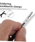 Hand holding soldering workbench clamp from Six Piece Flexible Soldering Alligator Clamps With Third Hand Tool And Magnifying Lamp