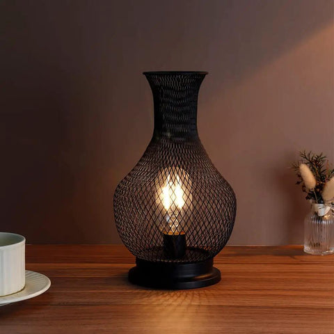 11 Inch Tall Metal Battery Operated Table Lamp in Vase Shape with Mesh Design, Cordless LED Bulb Light, Black Finish on wooden table