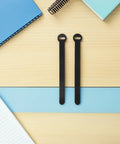 Super Solid 100 Piece Pack Of Self Adhesive Nylon Cable Ties With Cute Round Heads on a light wood surface near notebooks.