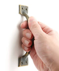 Hand holding 4 Pack 4 Inch Bronze Metal Cabinet Handles Rustic Drawer Pulls Vintage Curved Cupboard Handles For Kitchen Cabinets Furniture