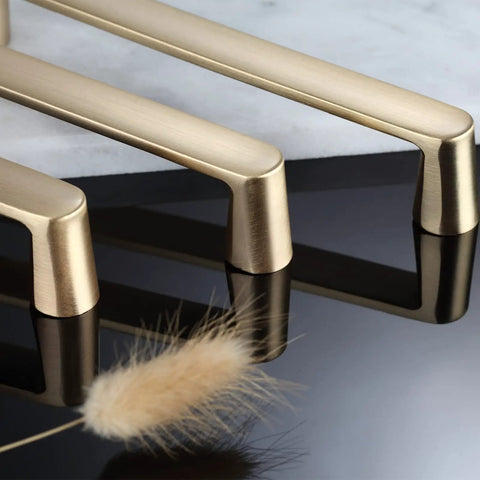 Close-up of brushed brass cabinet pulls 7 inch length 6.3 inch center to center gold handles, on glossy surface, side view