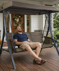 Man relaxing on Brenda 3 Seat Outdoor Porch Swing Glider with Adjustable Canopy on a porch
