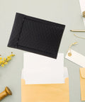Black Padded Bubble Mailer Envelopes 12x18 on desk with packaging supplies for small business mailing and shipping