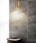 Top Tier Brass Wall Sconce With G4 Socket, Modern Bedside And Hallway Light, illuminating textured gray wall above laundry basket.