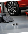 Retractable Spring Locating Pins Set Of 4 With Black Reset Spring on garage floor, next to car wheel and toolbox.