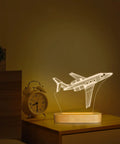 Lit 3D Airplane Illusion Night Light With Dimmable LED Wood Base on bedside, USB Powered Desk Lamp with airplane art.