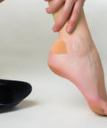 Self Adhesive Heel Protectors Soft Foam Cushion Pads For Shoes Wear Resistant Anti Blister Heel Grips on a foot against a black heel.