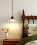 Wood Grain Pendant Light, 3 Color LED Resin Hanging Fixture for Bedroom above a nightstand with flowers.