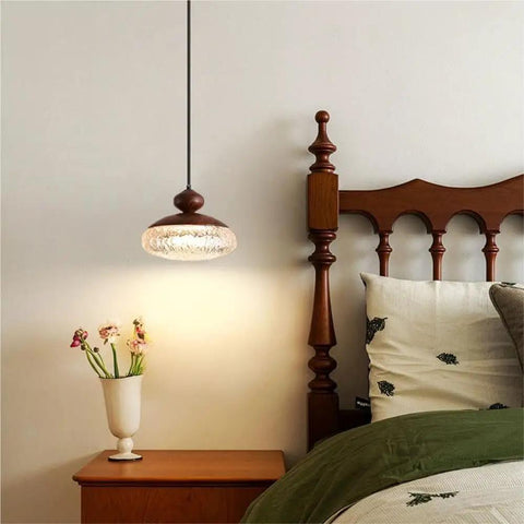 Wood Grain Pendant Light, 3 Color LED Resin Hanging Fixture for Bedroom above a nightstand with flowers.