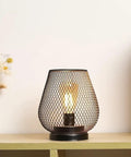 Metal Cage LED Lantern Battery Powered Cordless Accent Light on wooden shelf with warm white glow indoors