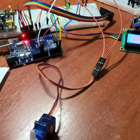 Front view of blue SG90 micro servo motor with three-wire lead on electronics workspace