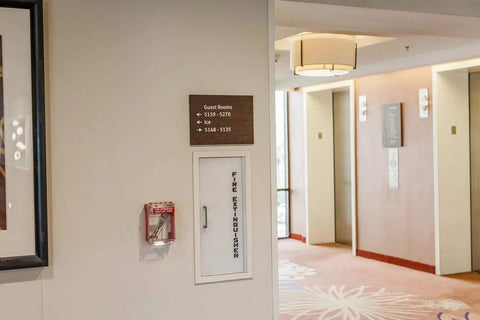High Vis Wall Case For Fire Sprinkler Shut Off Tool Heavy Duty Polycarbonate next to fire extinguisher in hotel corridor.