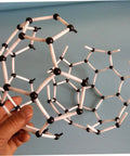 Hand holding C60 Molecule Model Kit For Classroom Learning And Teaching Aid Hands On Chemistry Set, showing black and white structure